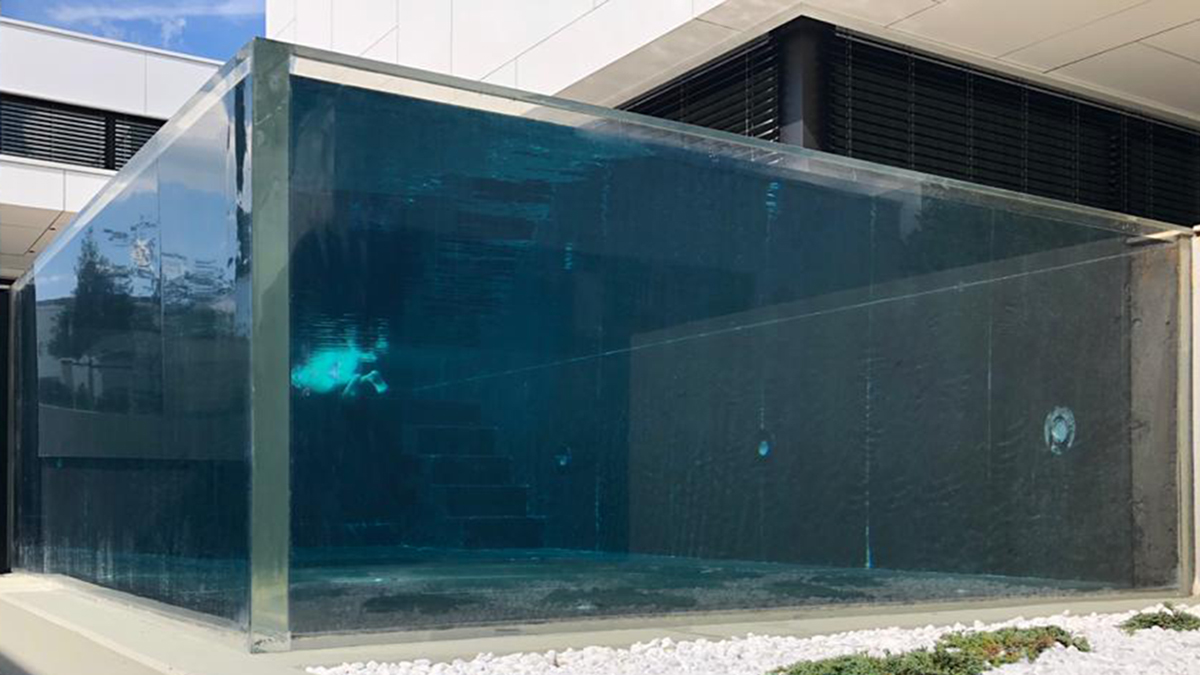 Acrylic pool viewing wall — transparent PMMA panel installed in hotel or residential pool, water depth and support interface visible