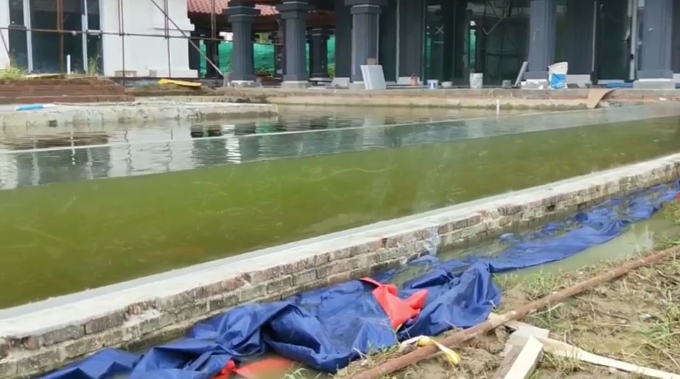 Water-filled condition of the long transparent acrylic pool wall in Myanmar with construction materials nearby