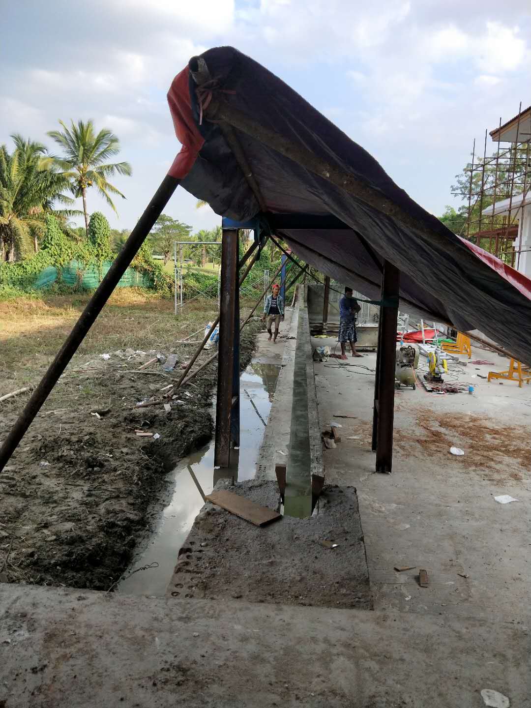 Temporary protective canopy over a long acrylic pool wall during construction in Myanmar