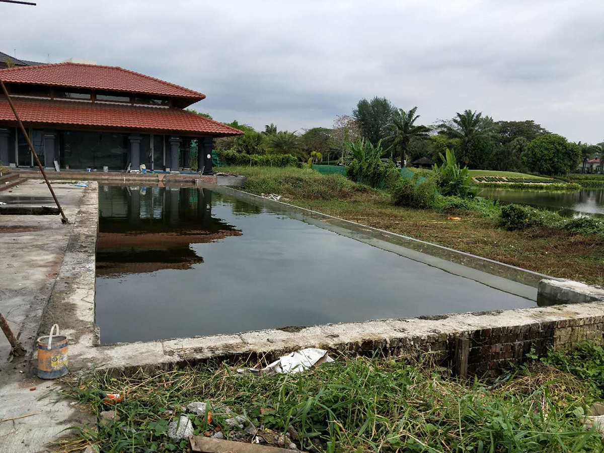 Private villa swimming pool in Myanmar during construction with a long transparent acrylic pool wall and water in the pool
